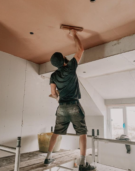 an image of a man on ladder scraping plasterboard from ceiling