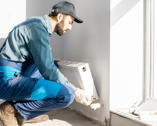 an image of a man removing radiator from off the brackets