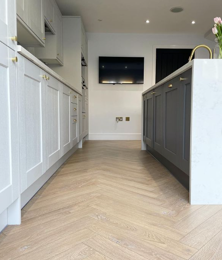 an image of herringbone laminate flooring in white kitchen