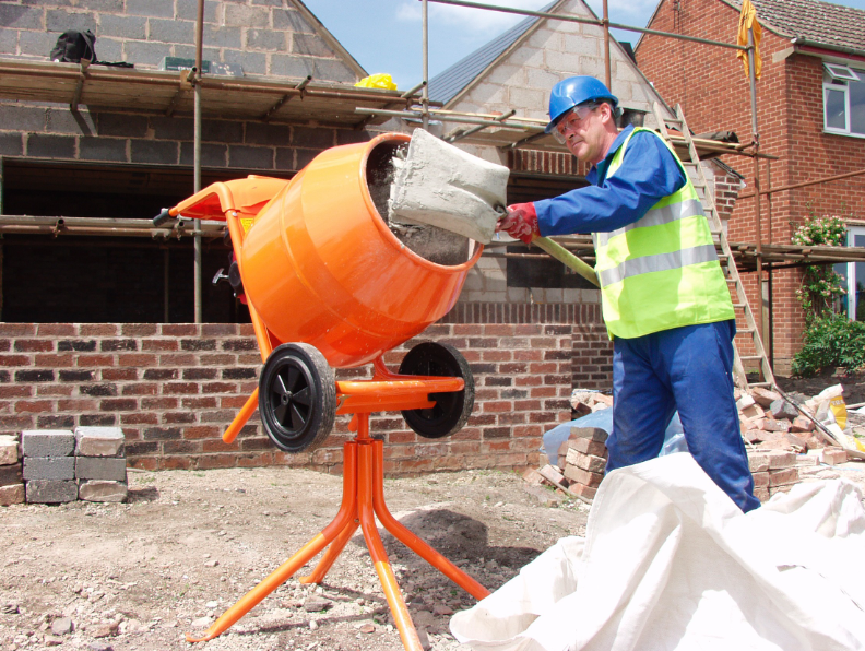 an image of a man putting cement mix in mixer