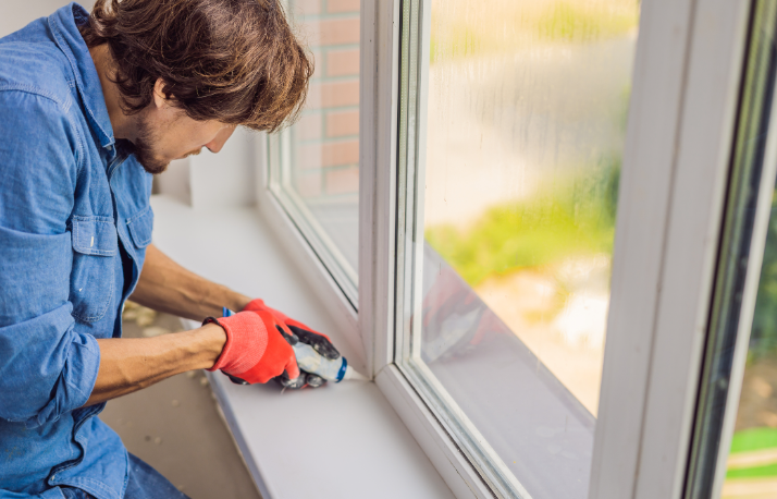 an image of man draught proofing windows with adhesive