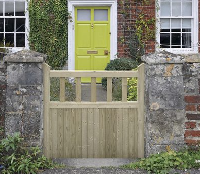an image of a white garden gate outside a cottage home, with a lime door