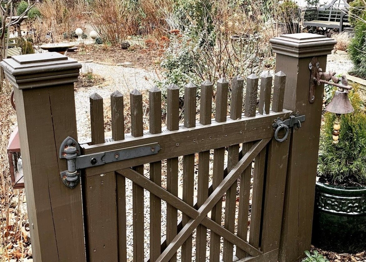 an image of a snowy wooden gate outside of a cottage home