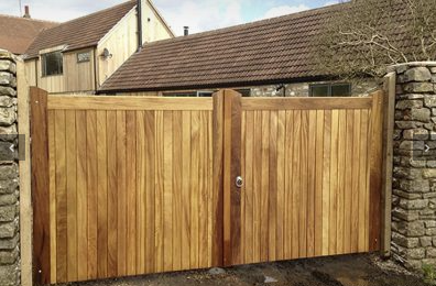 an image of a charlton driveway gate alongside a stone wall and outside a modern, big house