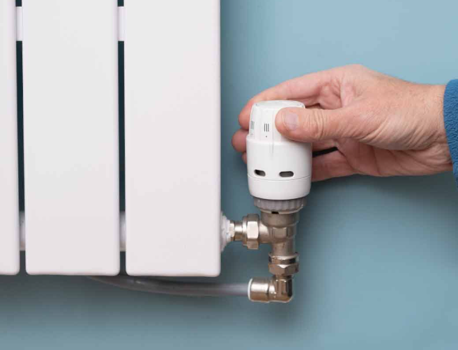 an image of a man turning the valve of the radiator off