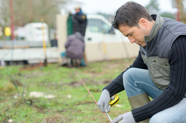 An image showing a man measuring the area for the artificial grass to be installed.