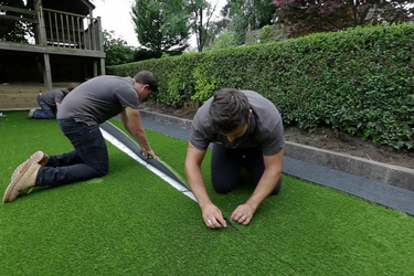 An image showing the tradesman jointing the 2 pieces of artificial grass together.