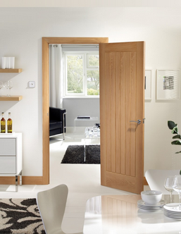 An image showing a suffolk original pre finished oak fire door in a kitchen/dining room. White floors, window behind door.