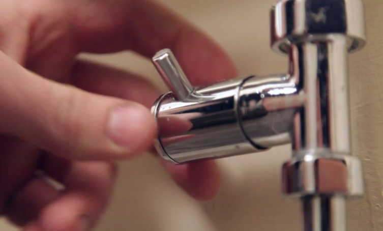 an image of a towel rail valve with someone turning it off. 