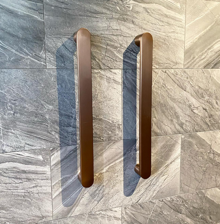 an image of a curved, brass chrome towel rail in a bathroom.